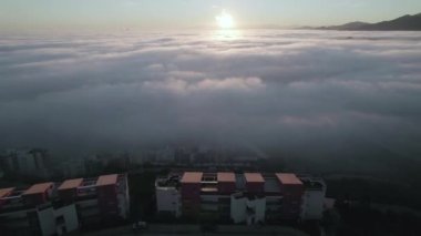 Top view drone footage of afternoon winter fog moving across houses on top of the hill in Spain. High-quality FullHD footage