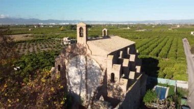 4K drone footage of a flight over Santa Barbara ancient church among orange trees in Spain. High-quality 4k footage