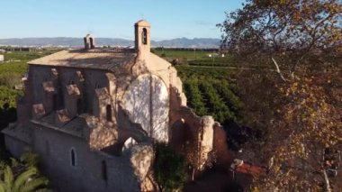 4K drone footage of a flight over Santa Barbara ancient church among orange trees in Spain. High-quality 4k footage