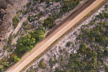 Drone aerial image of a small road carved among mountain walls in Via Verde of Oropesa, Spain