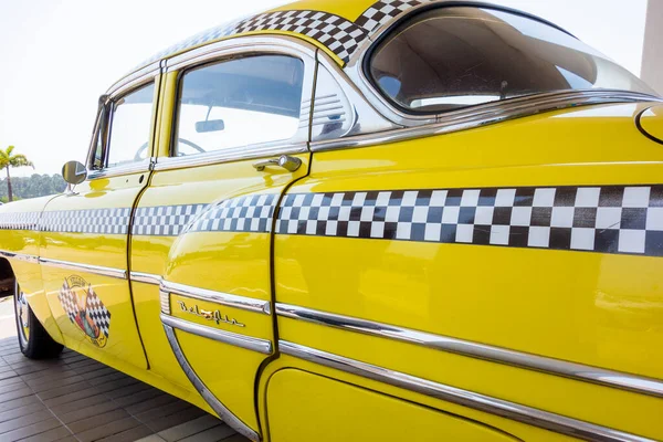 Horizontal close-up lateral image of an old restored yellow Chevrolet cab taxi. High-quality photo