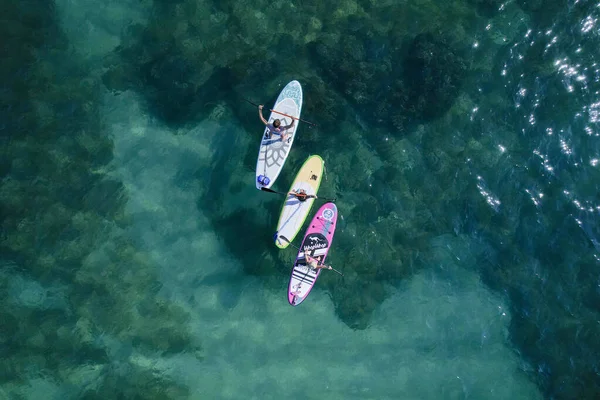 4K Footage group of 3 people Aerial drone view directly above of yoga on SUP stand-up paddle boards over a nice blue water