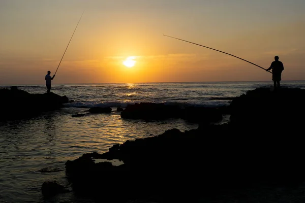 Two fishermen enjoying the last sunlight at the beach in Israel. High-quality photo