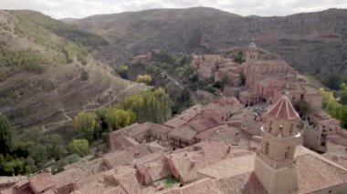 İspanya 'nın Teruel Eyaleti' ndeki yeşil kavak kuşları arasında Albarracin Köyü 'nün kırmızı çatısı ve ortaçağ evleri üzerinde insansız hava aracı uçuşu. Yüksek kalite 4K görüntü