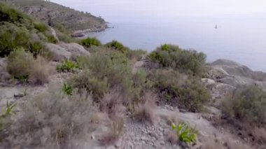 İspanya 'nın Akdeniz bölgesindeki kayalık bir uçurum ve mavi su dalgalarının üzerinden hızlı 4K drone uçuşu. Yüksek kalite 4K görüntü
