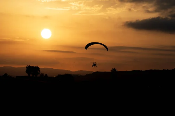 Paramotor trike silueti, sıcak bir turuncu yaz akşamında günbatımını arka plan olarak kullanıyor. Yüksek kaliteli fotoğraf.
