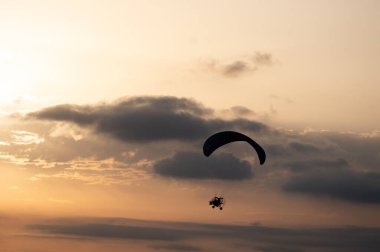 Paramotor tandem bir yaz akşamında güzel bulutlarla altın saatlerde uçan siluet. Yüksek kaliteli fotoğraf.