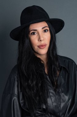 Portrait of a young beautiful brunette wearing a black hat with grey background. High quality photo