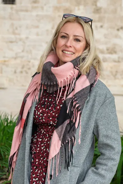 Pembe eşarp takan, kışlık giysiler giyen şık bir kadının portresi.