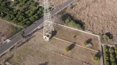 Aşağıdaki portakal ağaçlarını etkileyen güçlü bir elektromanyetik alanı olan yüksek voltajlı bir elektrik hattının havadan 4K açılı görüntüsü. Yüksek kalite 4k görüntü