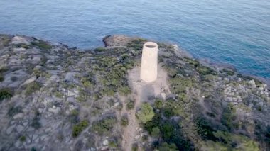 İspanya 'nın Oropesa del Mar kentindeki kayalıkların arasında bir kıyı şeridi ortaçağ savunma kulesinin insansız hava aracı görüntüsü. Yüksek kalite 4k görüntü