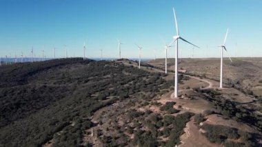 Hava manzarası, sakin bir manzaraya karşı yenilenebilir enerji üreten rüzgar türbinlerini güzelce yakalıyor.