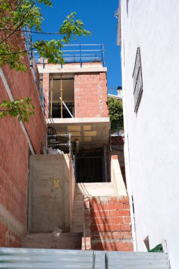 Açık mavi gökyüzünün altında tuğla ve iskelesi olan kentsel inşaat alanı.