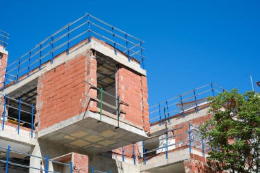 Açık mavi gökyüzünün altında tamamlanmamış binası olan modern kentsel inşaat alanı.