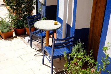 Akdeniz avlusunda mavi sandalyeli hoş bir açık kafe masası..
