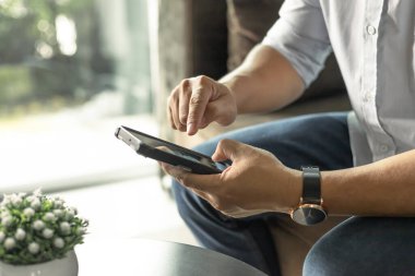 İş adamı iş konuşmak için cep telefonu kullanıyor. Adam kanepede oturuyor Evdeki oturma odasında.