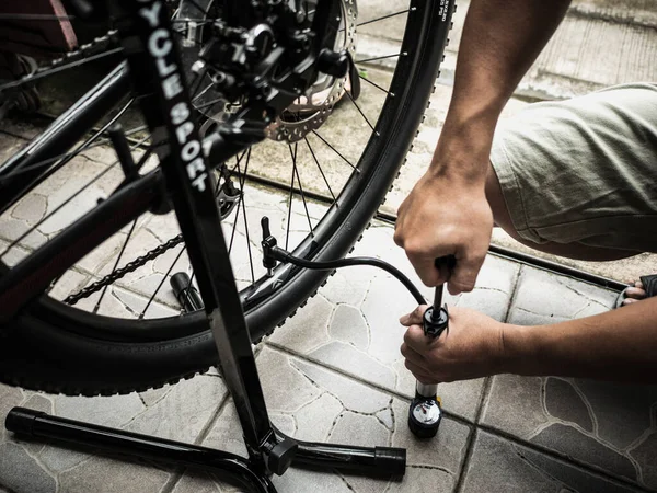a man\'s hands pumping up a bike tire using small pump.