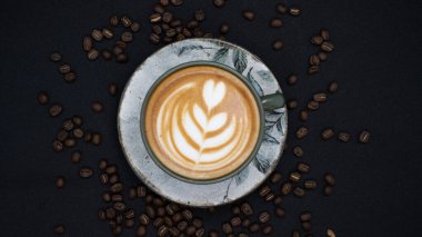 Siyah arka planda kızarmış fasulyeli bir fincan kahve.