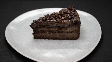 chocolate cake with cream and nuts on a black plate