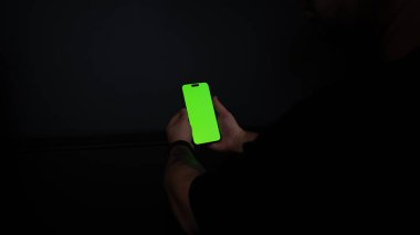 Siyah arkaplanda boş ekranı olan akıllı telefonu tutan