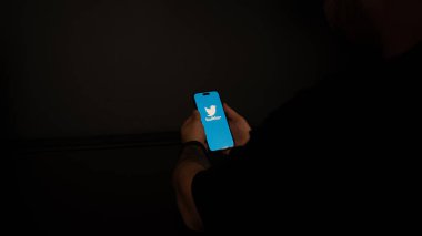 woman holding smartphone with black screen on dark background