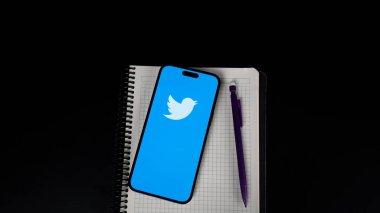smartphone with a pen and a notebook on a black background.