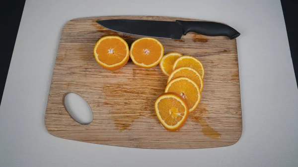 木のテーブルの上のナイフの新鮮なオレンジと黄色のスライス — ストック写真