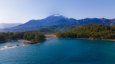 Dağ manzarası. Dağ gölü ve deniz manzarası. Ağaçların arasında dağ ve dağın zirvesinde kar
