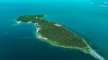 Mavi denizin ortasında bir ada. Ada ve kumsaldaki iskele... Gök mavisi denizin yanında.