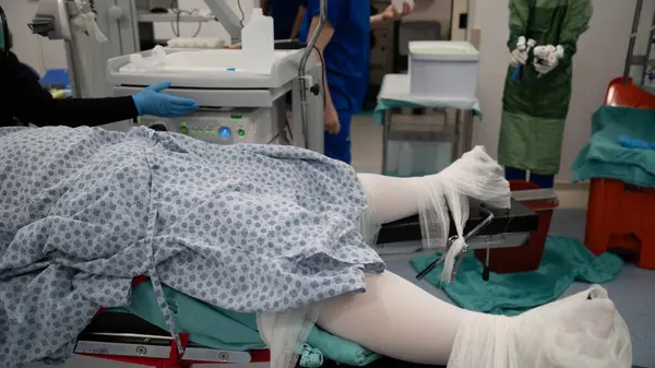 The patient who will be operated on is being prepared for surgery. Woman dressed in sterile clothes and compression socks in the sterile field, in the operating chair