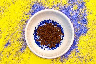 Mavi benekli sarı bir arka planda, süs kasesinde kahve tanelerinin makro fotoğrafı.