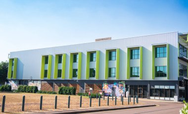 Basit renk ve kalay kaplama kullanımı basit bir kutucuk biçimindeki ticari binaya karakter ekler