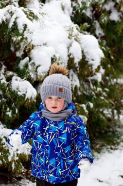 Bir çocuk parkta yürüyor, kardan adam heykeli yapıyor ve kışın çok kar yağdığında kızağa biniyor.