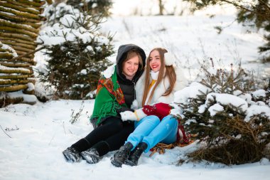 Two Ukrainian sisters are walking in the park in winter, smiling and wearing warm, beautiful clothes. Professional teeth cleaning