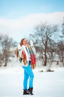 Portrait of a girl with closed eyes and red lips. White gloves in winter. Blue sky in January. A frozen lake