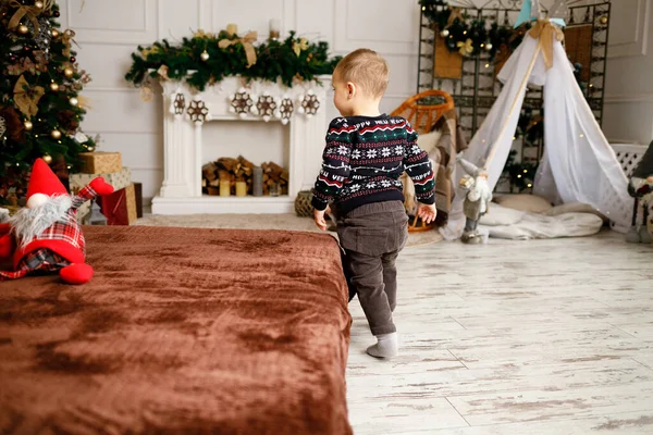 A boy at home runs to the Christmas tree to find presents from Santa. Warm winter clothes