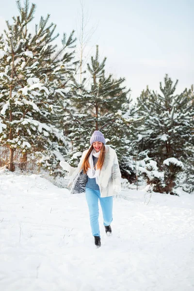 A walk in a winter forest in Poland. Warm dress. Pine trees in the snow. Winter shoes. A lot of snow is falling from the trees