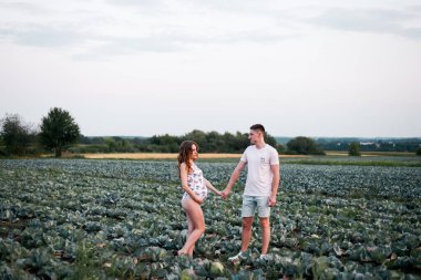 A couple in love searches for a baby in a cabbage. Funny sentence. Pink swimsuit and men's summer clothes