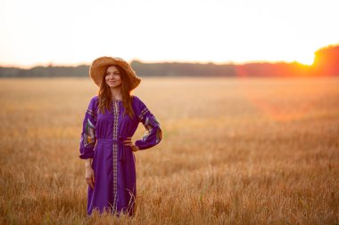 A girl in a straw hat at sunset in a dress