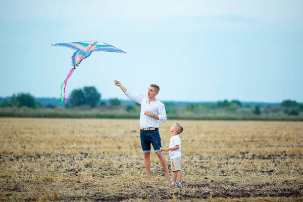 Father and son fly a kite on the field