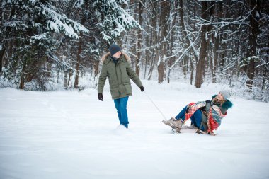  husband sleds his wife in the snow in winter. Happiness is in simple things