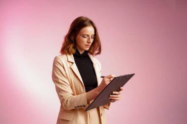 Business lady with papers on pink background wearing glasses. Solving important tasks in the office