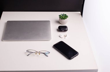 Office supplies on the table in the office. Laptop for work and financial reports, phone, headphones, glasses on a white table. Copy space