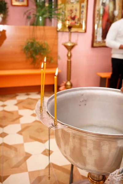 Candles and a cross in an Orthodox church during the Sacrament of Baptism