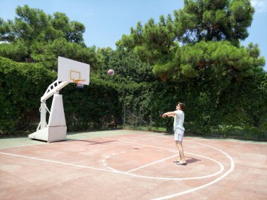 A tourist in Turkey plays basketball outside and throws the ball into the hoop at the hotel