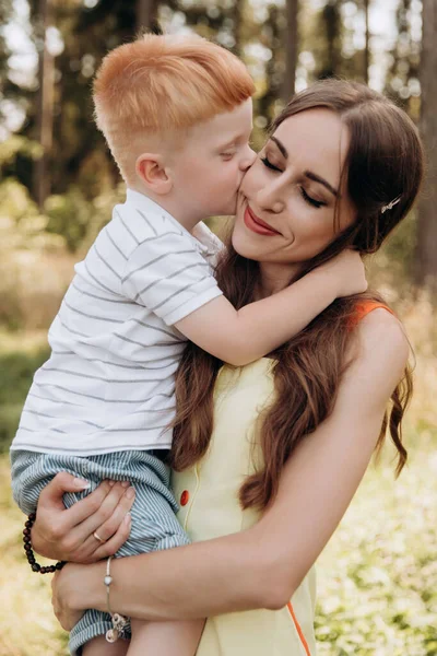 A red-haired son kisses his mother on the cheek. Family values are the most precious
