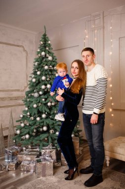 Ukrainian family is standing near the Christmas tree and waiting for Christmas and many gifts