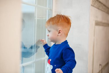 The view of a red-haired Ukrainian boy who looks out the window and looks at his parents after working with sweets