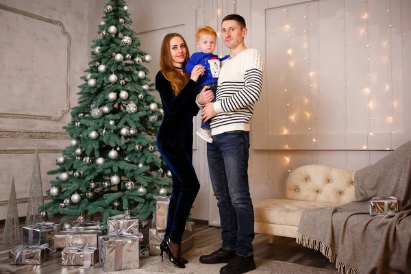 Ukrainian family is standing near the Christmas tree and waiting for Christmas and many gifts. Copy space