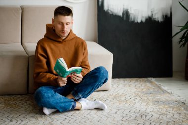 A young man narrating an old novel book to his followers by looking at his cell phone camera. Front phone camera view. Concept of liking reading books